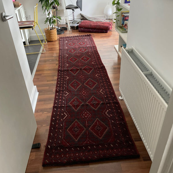 Long red patterned rug on a wooden floor in a home setting