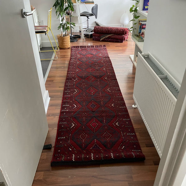 Red Mushwani patterned runner on a wooden floor in a home setting