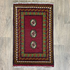 Small Afghan Aqcha handmade wool doormat featuring traditional red and navy elephant foot Mori gul patterns, styled on a light oak wood floor.