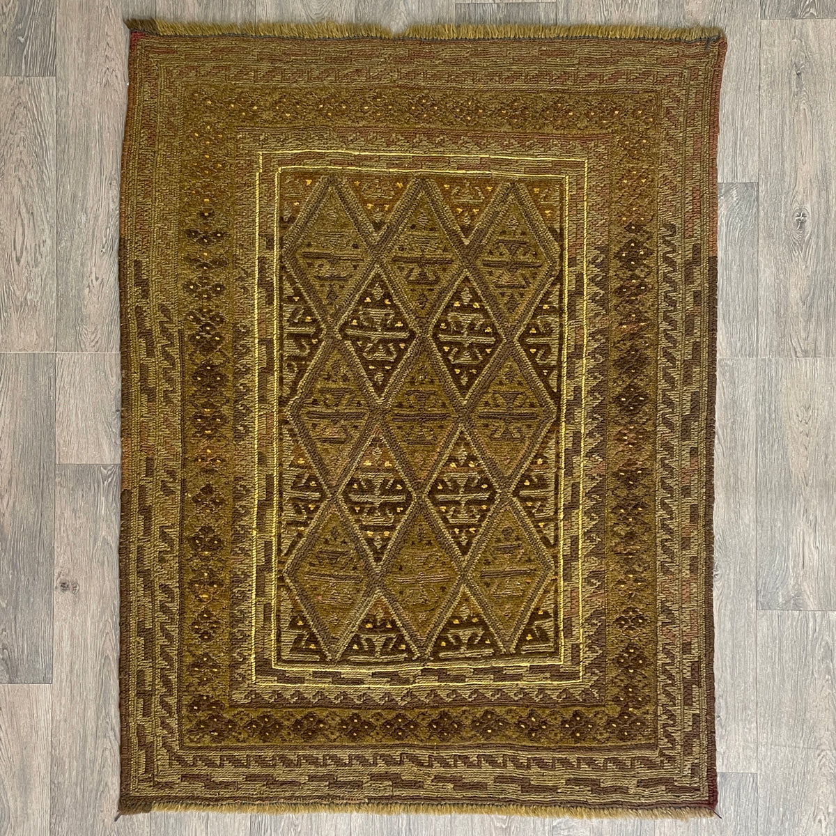 Handmade Afghan brown Mushwani tribal rug featuring a unique combination of flat-weave kilim and raised wool pile geometric diamond patterns, displayed on a light oak wood floor.
