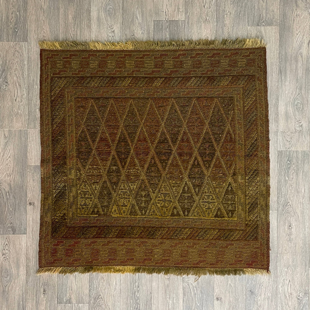 Handmade Afghan brown Mushwani tribal rug featuring a unique combination of flat-weave kilim and raised wool pile geometric diamond patterns, displayed on a light oak wood floor.