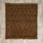 Handmade Afghan brown Mushwani tribal rug featuring a unique combination of flat-weave kilim and raised wool pile geometric diamond patterns, displayed on a light oak wood floor.